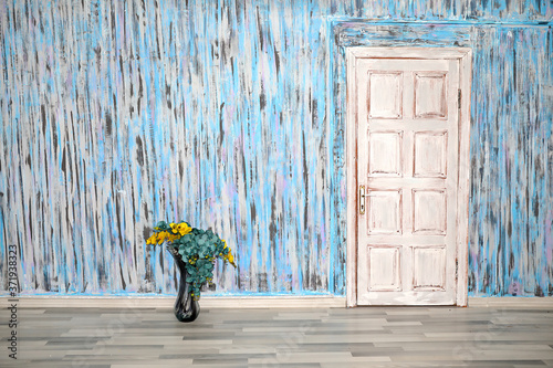 A mottled wall. A mottled wall. A texturally artistically painted wall with a vintage door and a flower in a vase . photo