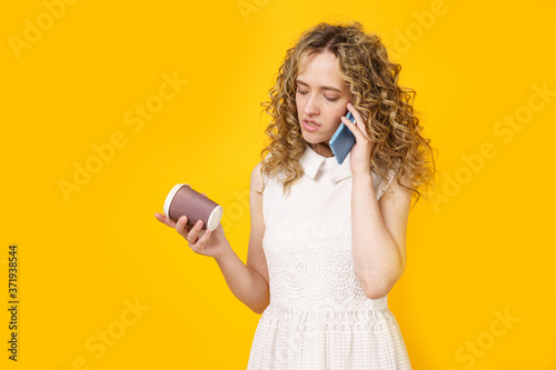 Portrait of a young woman who is emotionally talking on the phone, drinking coffee. Female portrait.