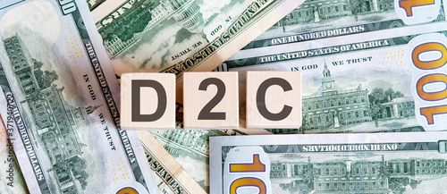 Concept words D2C on wooden blocks on a beautiful background from dollar bills.