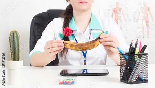 Doctor urologist andrologist holds a spoiled banana in his hands. The concept of male diseases, male menopause, ejaculation disorders photo