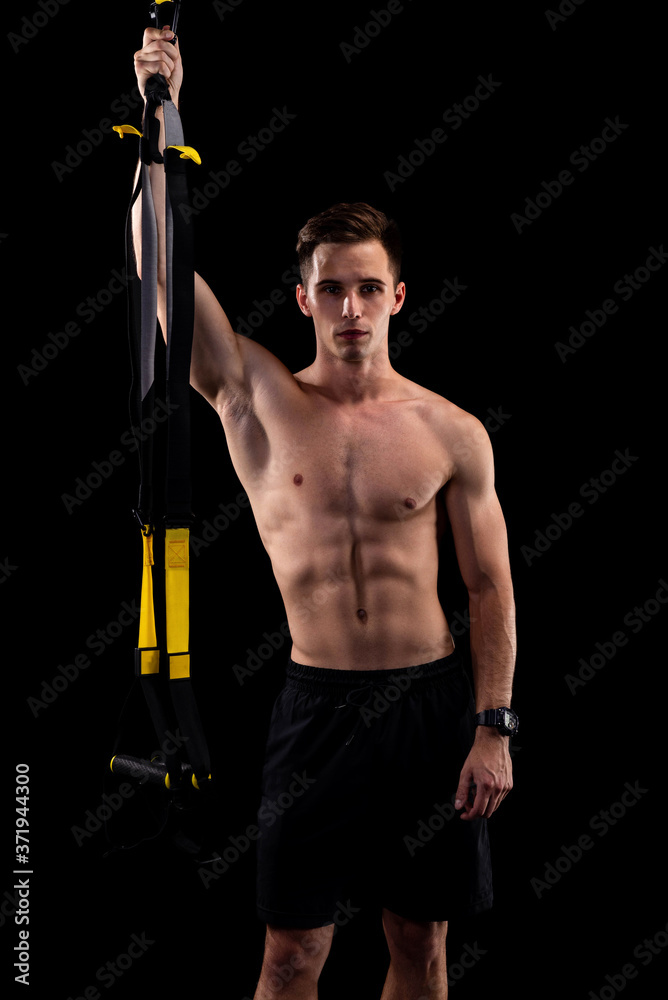 Young muscular man with loops isolated on black background. Total resistance exercises Young muscular man with loops isolated on black background. Total resistance exercises