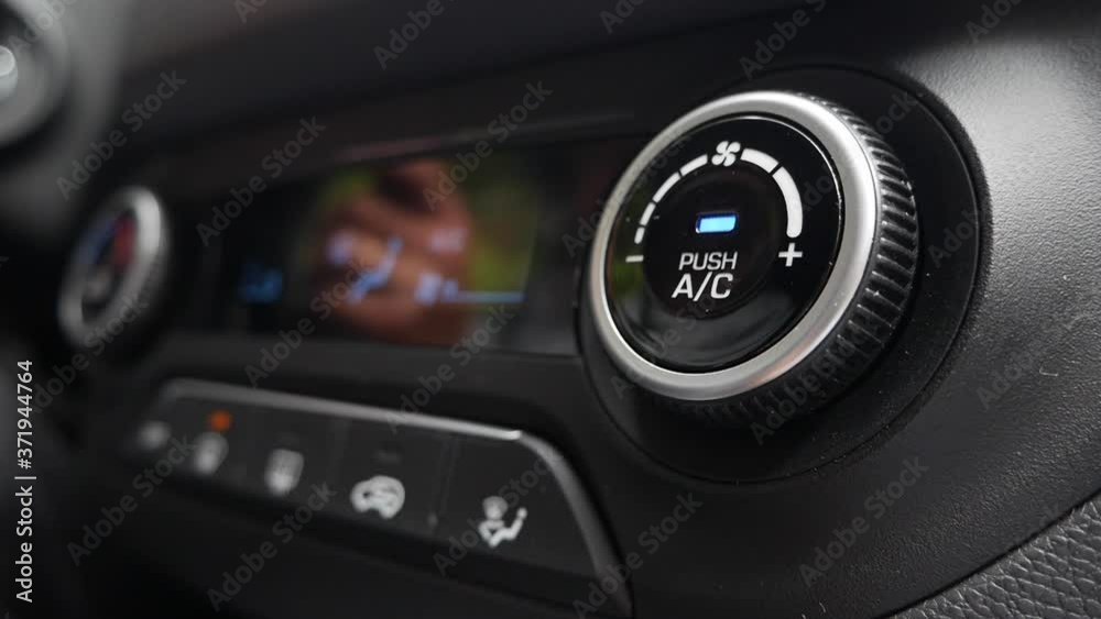 Close-up of pushing a button to turn on the air conditioner in a car. The mans hand turns the button Close-up of pushing a button to turn on the air conditioner in a car. The mans hand turns the button