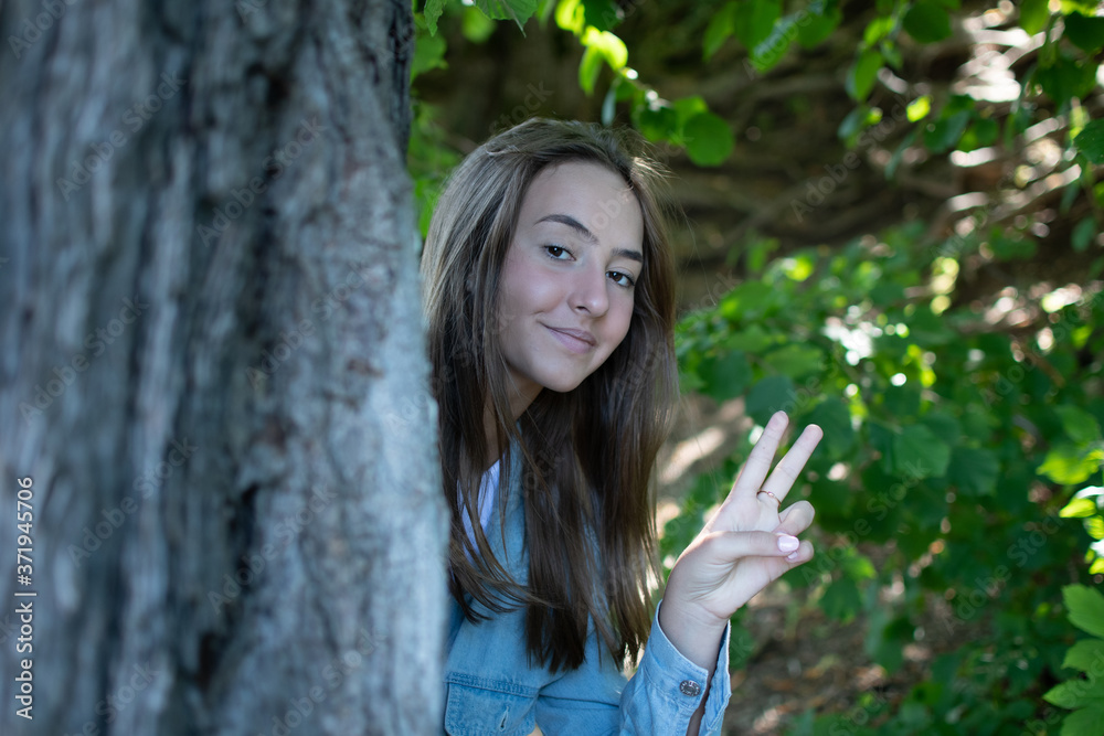 Beautiful girl making victory gesture in nature Beautiful girl making victory gesture in nature