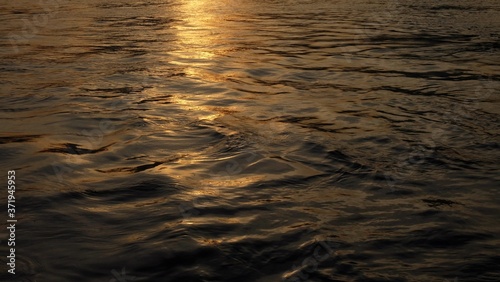 Blurred golden light sunset reflection on river waves for backdrop background 