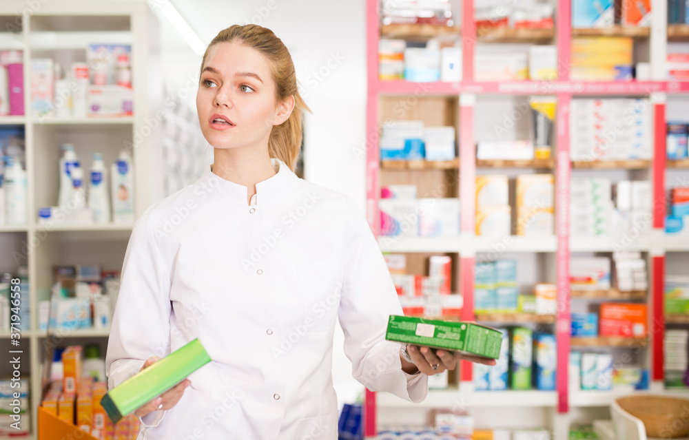 Portrait of smiling friendly female druggist in white coat working in pharmacy. High quality photo