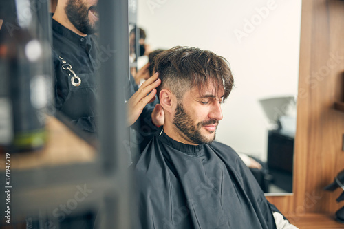 Positive delighted male person being in barbershop