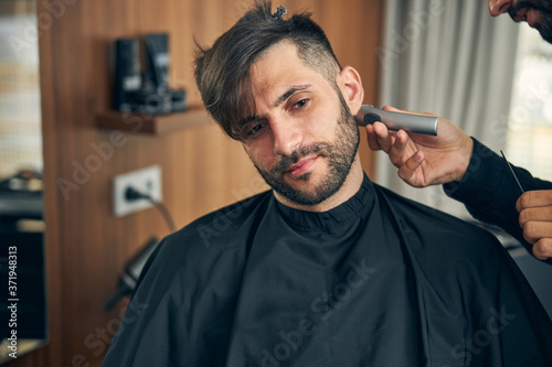 Positive delighted bearded man being in barbershop