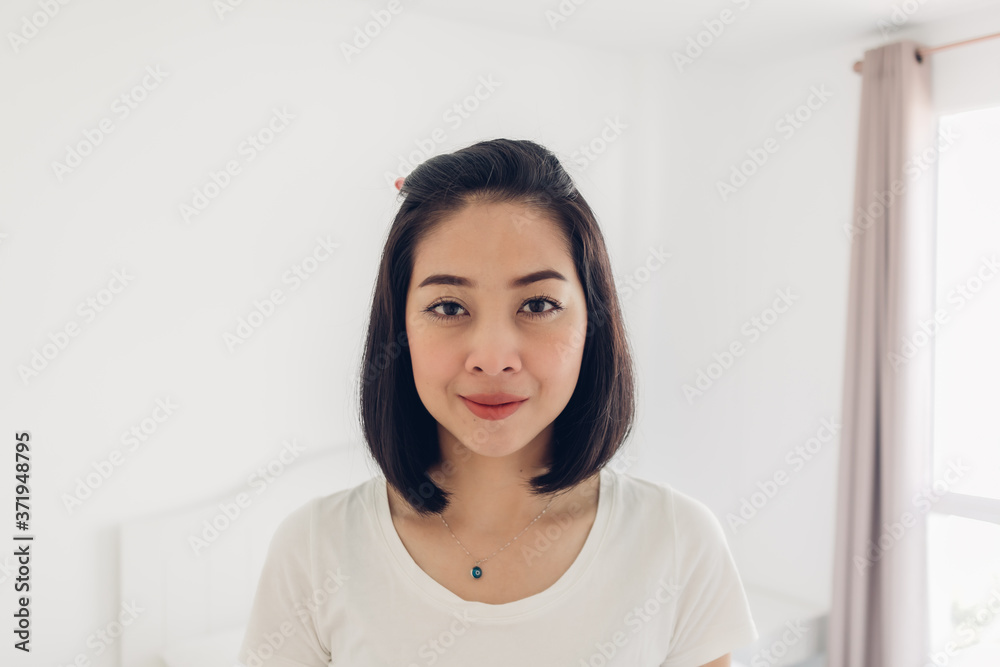 Straight portrait of Asian woman standing in white bedroom. Straight portrait of Asian woman standing in white bedroom.