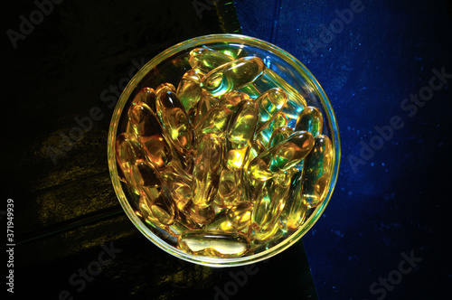 omega 3 capsule. In a glass bowl on a colored background.