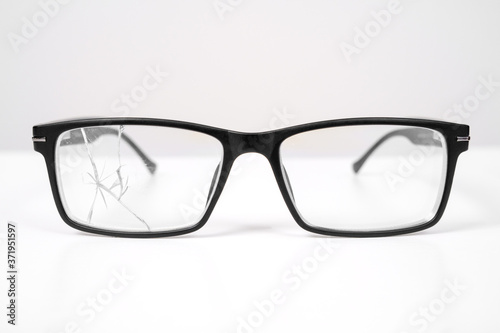 close up of broken black glasses on a white background. vision examination and repair.