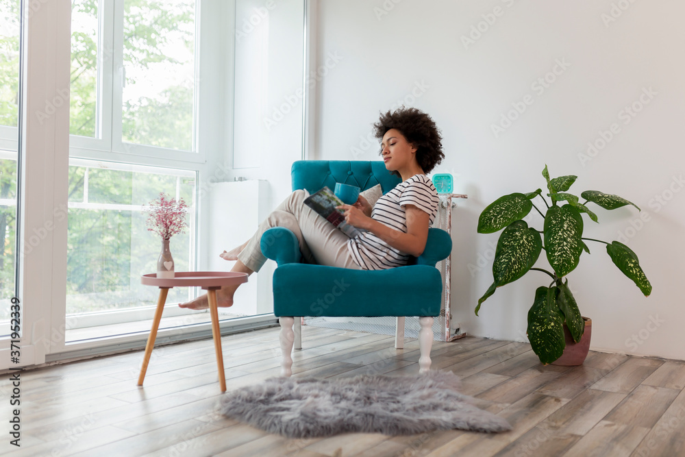 Obraz premium Woman reading a magazine and drinking tea