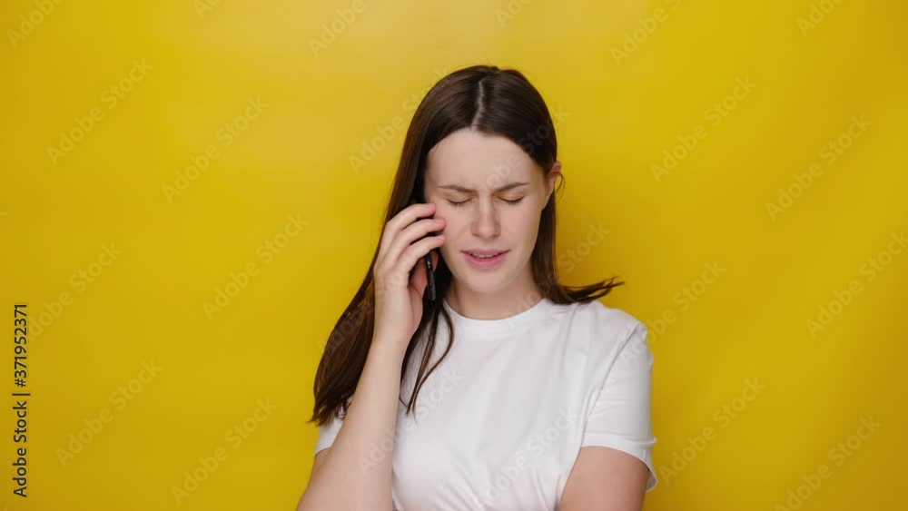 Concerned woman talking on smartphone solving problems, worried girl discussing business issue speaking by cell mobile making call having difficult conversation, isolated on yellow studio background Concerned woman talking on smartphone solving problems, worried girl discussing business issue speaking by cell mobile making call having difficult conversation, isolated on yellow studio background