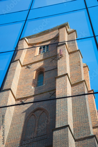 Reflection of an old, gothic church in the glass of a new s, a modern building against a blue sky in a horizontal position, a screensaver for a mobile phone