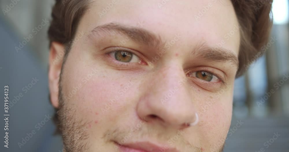 Close up of handsome man face smiling. Caucasian male face outdoors in city. Happy brown eyes looking at camera. Deep look. Positive emotions. Good mood. Face expression. Emotions concept