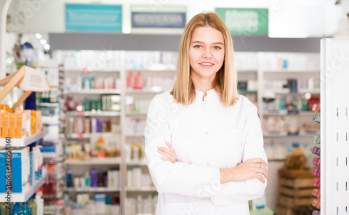 Cheerful woman pharmacist standing with arms crossed in interior of pharmacy. High quality photo Free Download Cheerful woman pharmacist standing with arms crossed in interior of pharmacy. High quality photo - GFXLoad