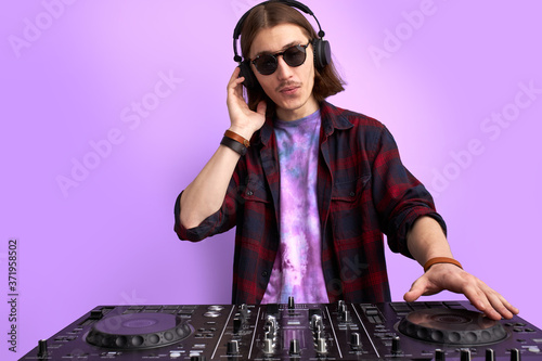 modern club DJ playing mixing music on vinyl turntable, isolated in studio. caucsaian male perform techno style music, enjoy playing on equipment