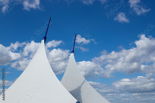 Awnings in sail shape against a blue sky background with white fluffy clouds