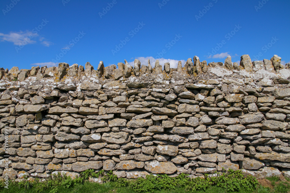 A dry stone wall against clear blue sky.