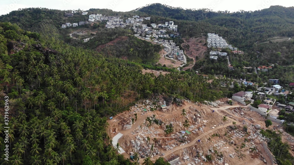 Obraz premium Tropical terrain covered with endangered forests and luxury villas. Drone view of large tropics with ecosystem disturbance due to buildings and deforestation. Koh Samui. Coconut palm plantations.