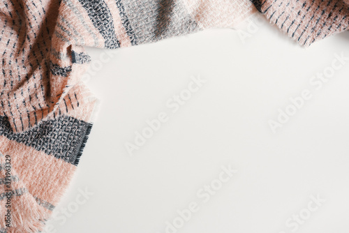 Woolen scarf of pink and gray color on white background, top view, copy space. Fall or winter season