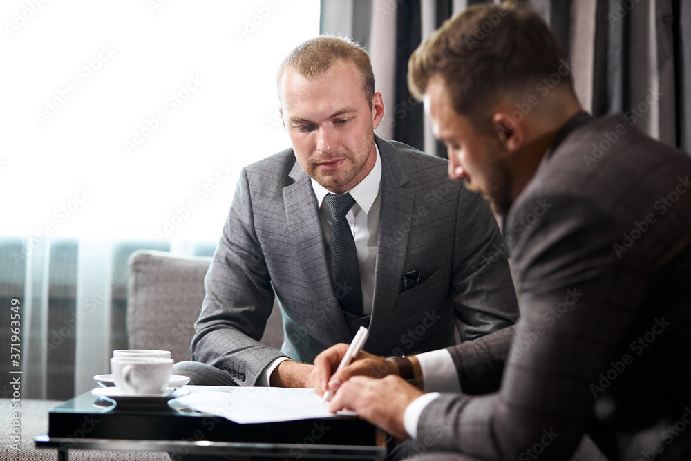 two caucasian businesspeople sit discussing ideas, strategies and plans for future work. handsome guys in formal wear coworking two caucasian businesspeople sit discussing ideas, strategies and plans for future work. handsome guys in formal wear coworking