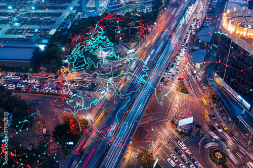 World planet Earth map hologram on aerial view of road, busy urban traffic highway at night. Junction network of transportation infrastructure. The concept of success in logistics business.