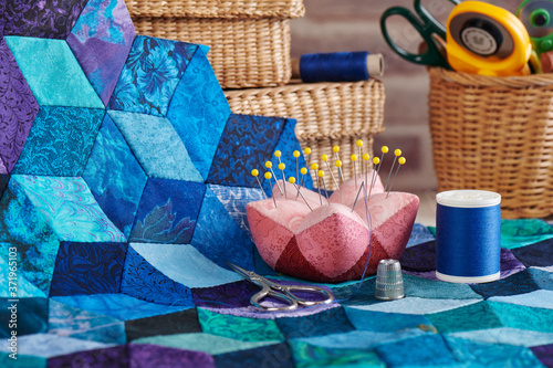 фотографія Accessories for sewing, fragment of tumbling blocks quilt and baskets with tools