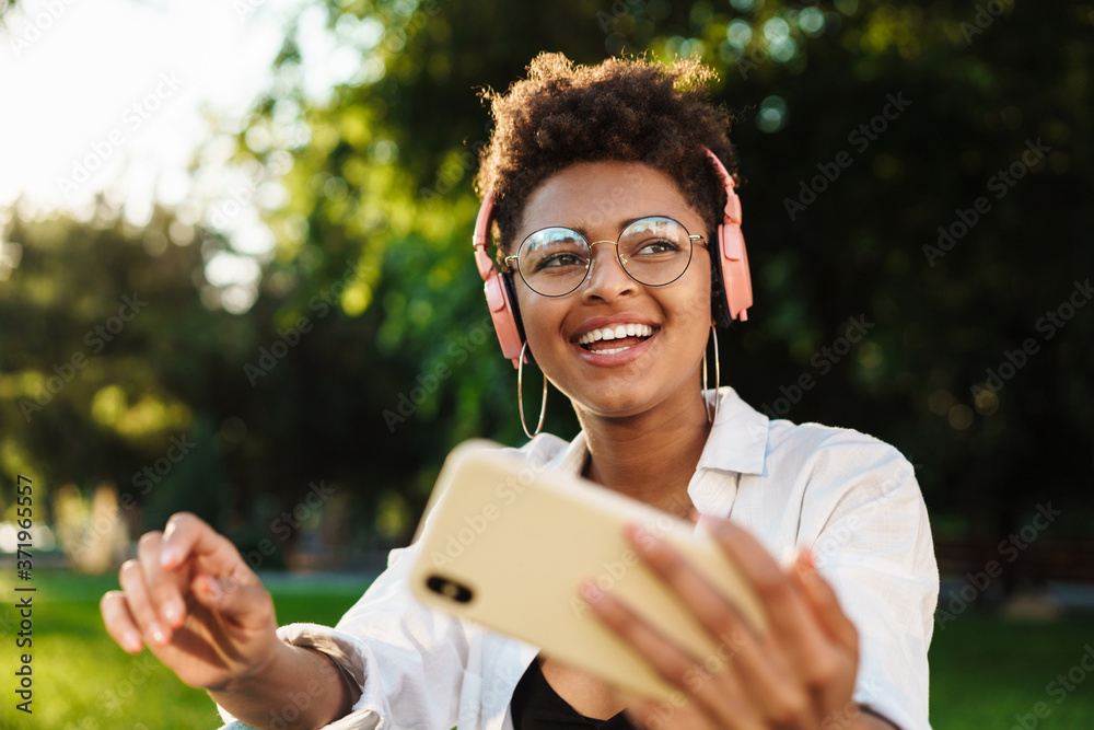 Fototapeta premium Woman outdoors in park listening music