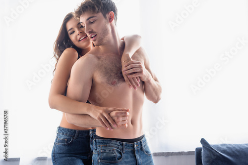 young brunette woman hugging shirtless boyfriend at home