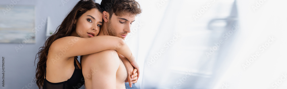 panoramic orientation of young woman in bra hugging shirtless boyfriend and looking at camera panoramic orientation of young woman in bra hugging shirtless boyfriend and looking at camera