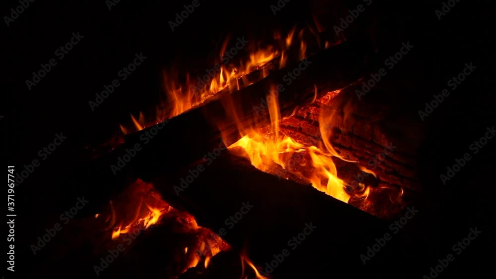 Fire wood and campfire. Orange flame inside a wood burner stove against black background Fire wood and campfire. Orange flame inside a wood burner stove against black background