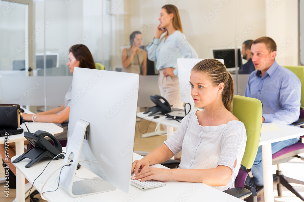 Young businesswoman concentrated on work with laptop in modern busy coworking space