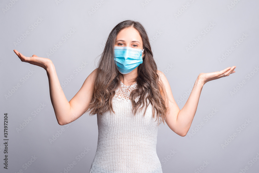 Portrait of young woman wearing medicinal mask and making DONT KNOW gesture. Portrait of young woman wearing medicinal mask and making DONT KNOW gesture.