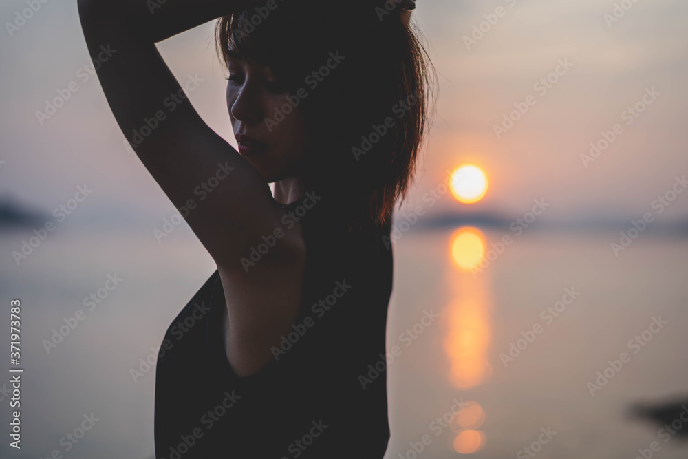 夕陽の海にいる女性