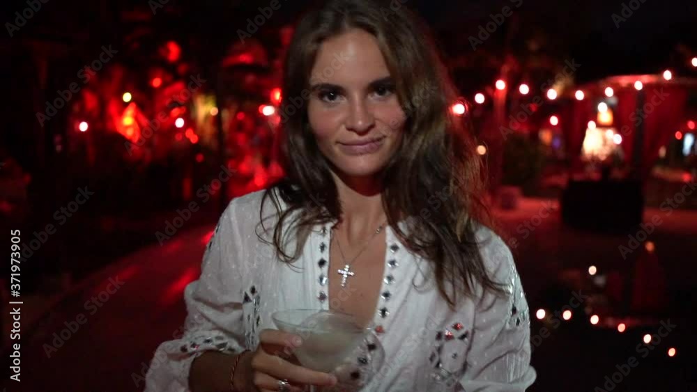 closeup of a beautiful young girl in a white dress dancing incendiary in a nightclub with a cocktail in her hands closeup of a beautiful young girl in a white dress dancing incendiary in a nightclub with a cocktail in her hands