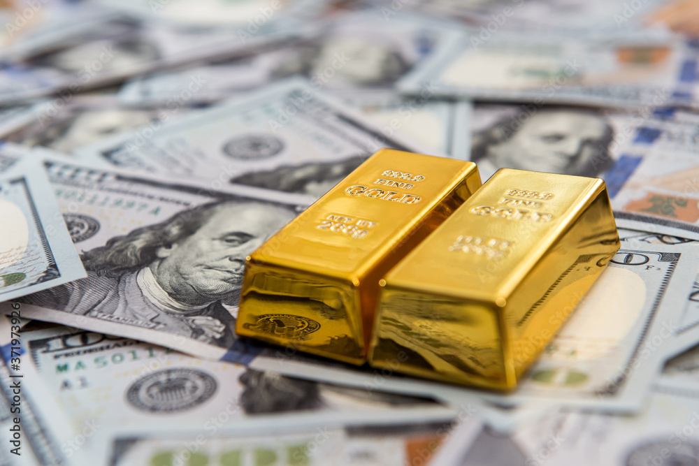 Expensive gold bar lying on dollar bills Expensive gold bar lying on dollar bills