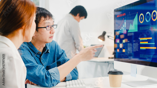 Millennial group of young Asia businessman and businesswoman in small modern urban office. Japanese male boss supervisor teaching intern or new employee korean girl helping with difficult assignment.