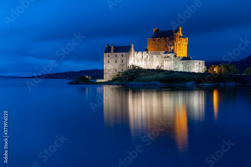 Eilean Donan Castle in Scottish highlands with water reflection photographed at blue hour after sunset