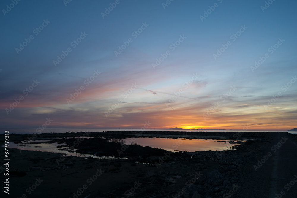Italy, Tuscany, Grosseto, Maremma, Marina di Alberese, Natural Park of Maremma, also called Uccellina, sunset on the mouth of the river Ombrone; the sun sets behind the island of Elba Italy, Tuscany, Grosseto, Maremma, Marina di Alberese, Natural Park of Maremma, also called Uccellina, sunset on the mouth of the river Ombrone; the sun sets behind the island of Elba