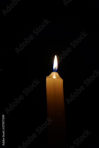 Burning candle on a black background in the dark at night.