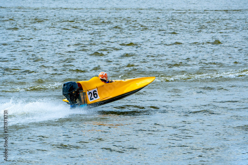 Yellow powerboat with number 26 go fast along the lake