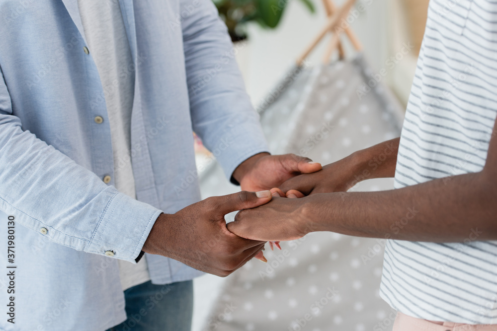 cropped view of african american couple holding hands at home cropped view of african american couple holding hands at home