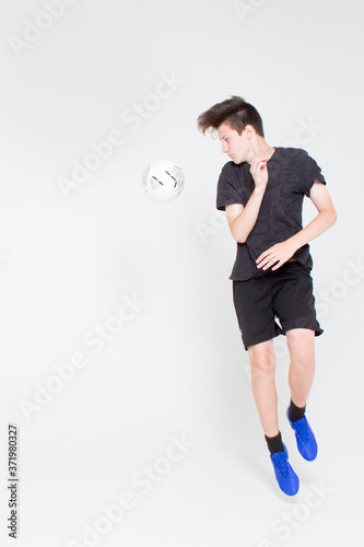 A young boy in a black sports t-shirt and shorts, training and playing with a soccer ball.