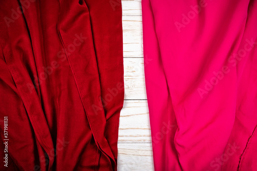 Two pieces of red and pink textile on white wooden board