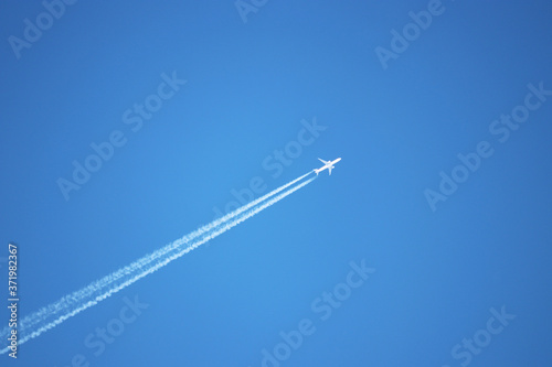 Trail of jet plane on clear blue sky. Airplane flying with white contrail