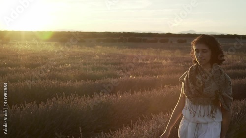 A woman with white dress walking across a lavender field.