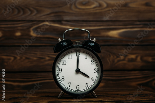Clock on a wooden background. The clock shows the time of four o'clock in the afternoon. The clock shows the time four o'clock in the morning. An image of a retro clock showing 04:00 pm/am. Copy space