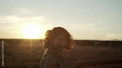Woman smiling and looking at the camera in a lavender field on sunset