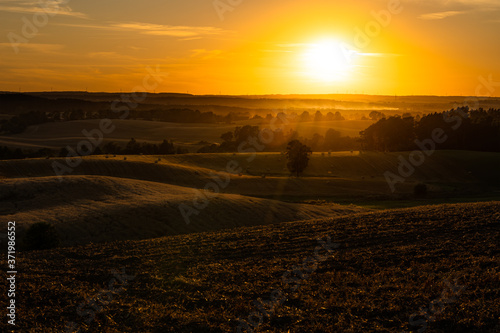 Sunset over rural fields with golden sunlight. Dusk in the countryside.
