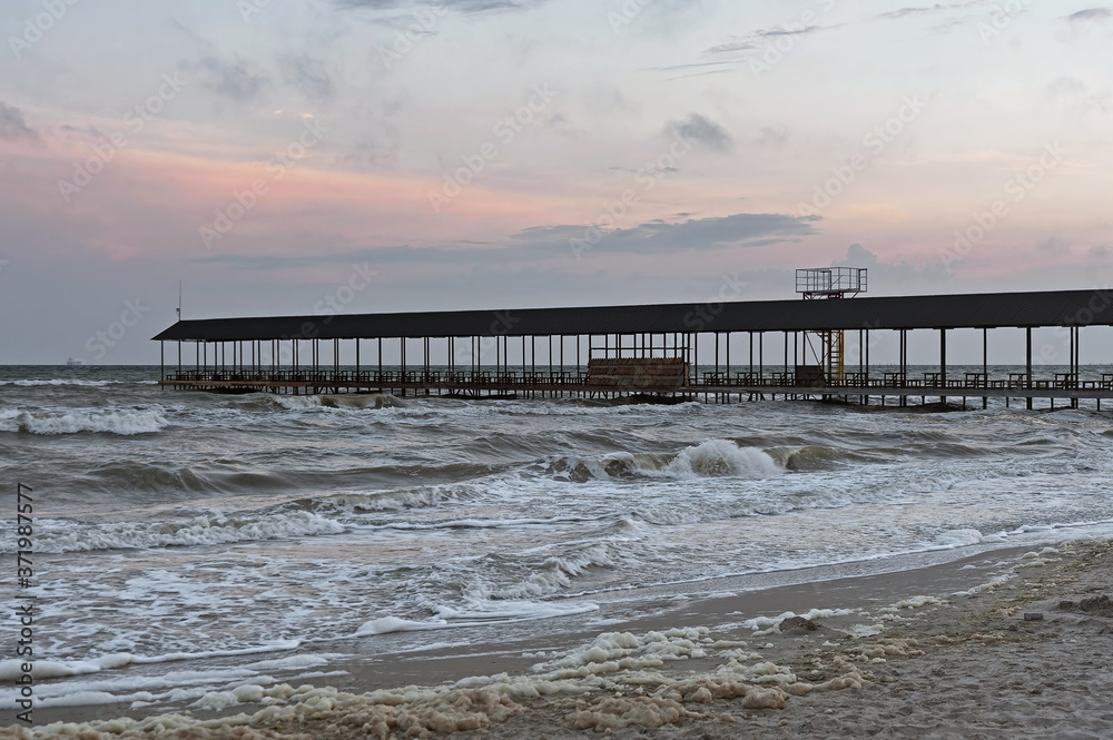 The seaside evening landscape with the empty simple covered pier of Koblevo in Ukraine The seaside evening landscape with the empty simple covered pier of Koblevo in Ukraine